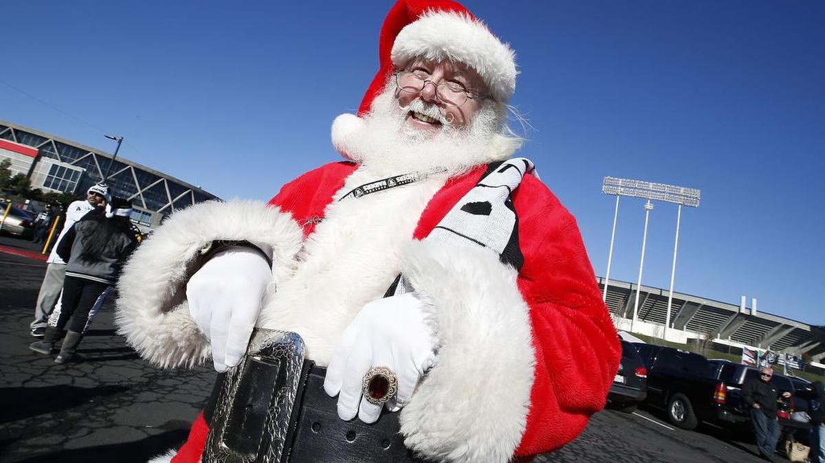 Un fanático de Oakland Raiders vestido como Santa Claus posa para las fotos antes de un partido de fútbol en Oakland, California, el sábado 24 de diciembre de 2016.