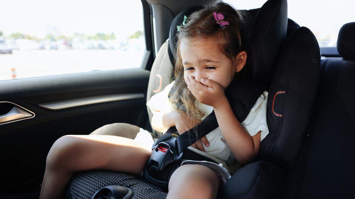 Niña sufre de nauseas sentada en la parte de atrás de un carro.