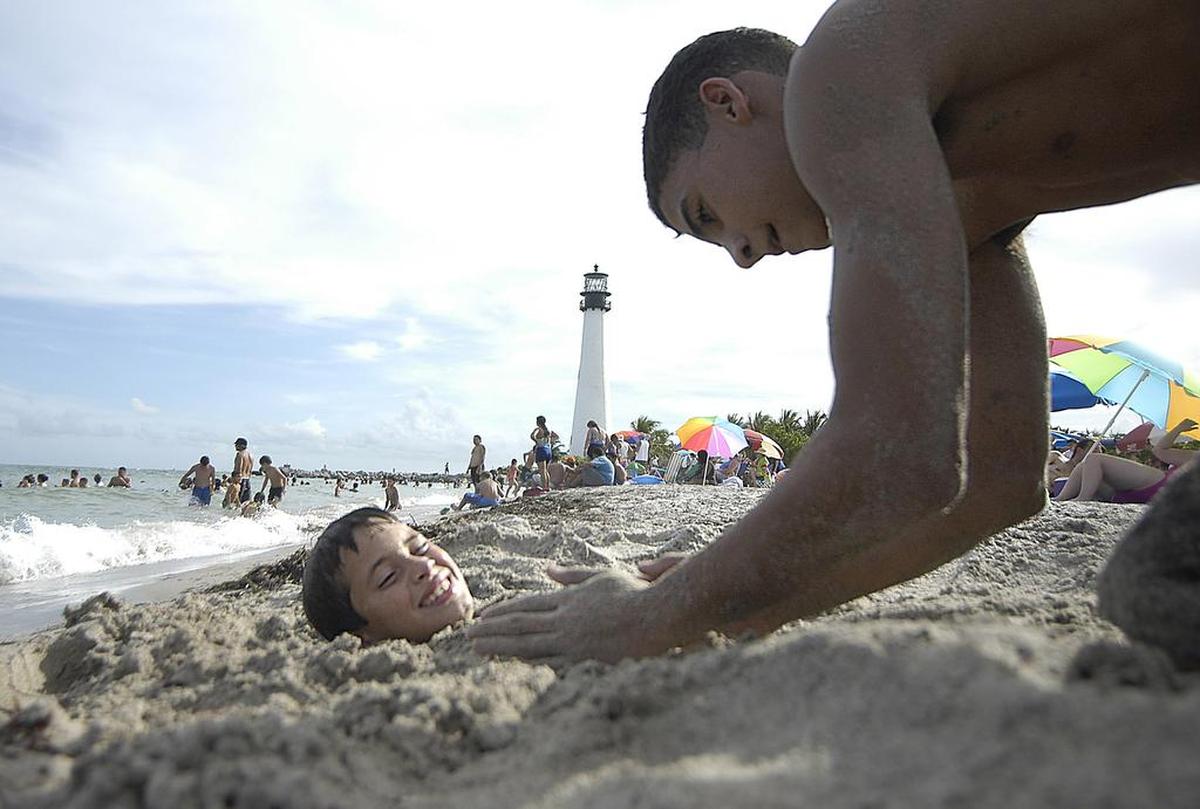 Oscar Peraza es enterrado hasta el cuello en la arena por su primo Rolando Fernández en el Bill Baggs Cape Florida State Park, en Key Biscayne. Es considerada una de las mejores playas de Estados Unidos.