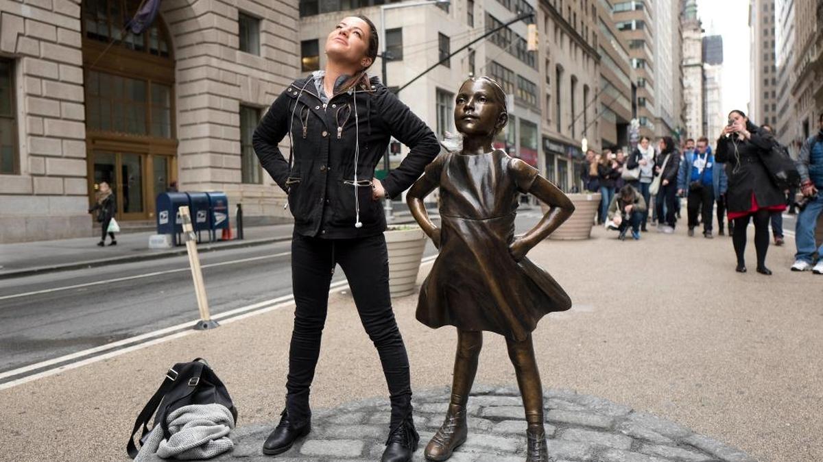Una mujer posa junto a la estatua titulada “Fearless Girl” en Wall Street, en Nueva York.