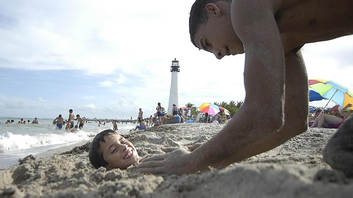 Oscar Peraza es enterrado hasta el cuello en la arena por su primo Rolando “Roly” Fernández cerca del faro histórico en el Bill Baggs Cape Florida State Park, en Key Biscayne. El parque es un destino popular para senderistas y ciclistas, y ha sido elegido como una de las mejores playas de Estados Unidos.