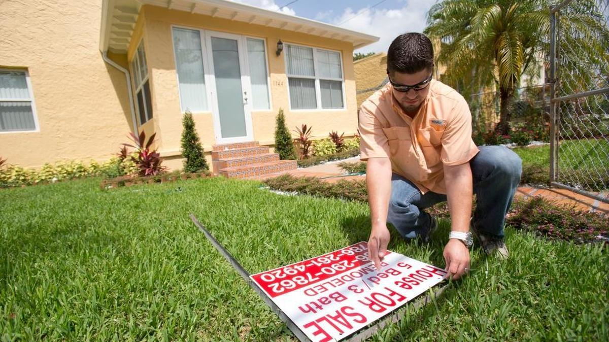 Un vendedor de bienes raíces pone un letrero de venta en el vecindario de Shenandoah en Miami. 