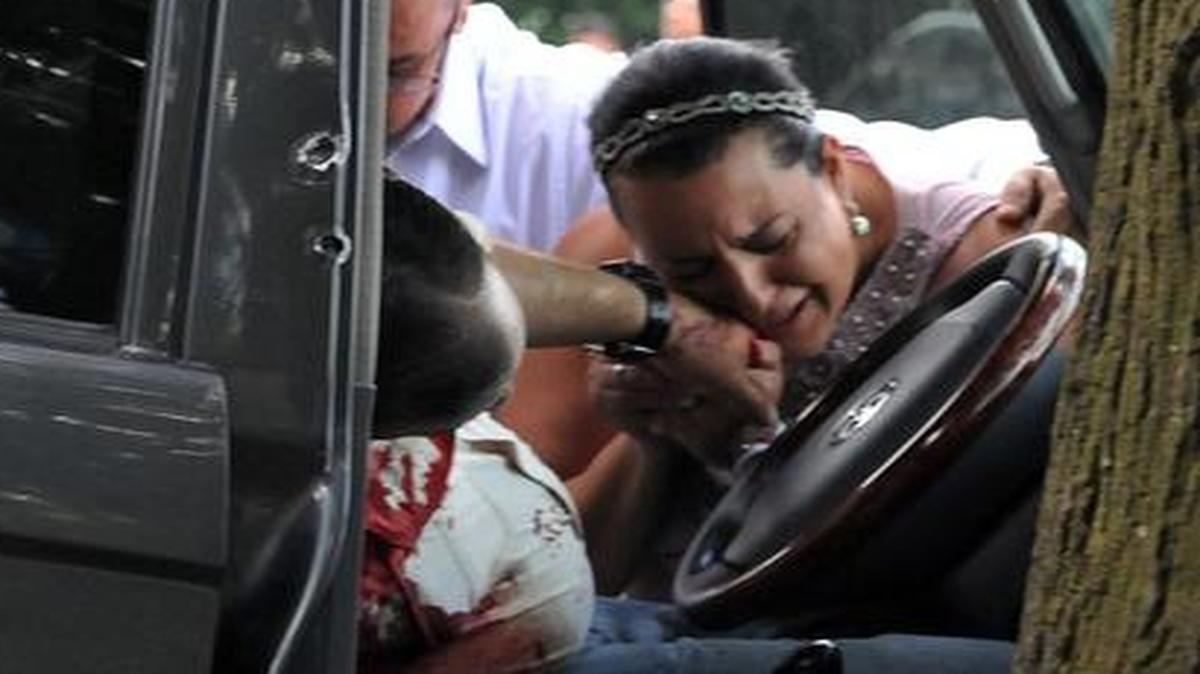 
Una mujer llora estrechando la mano del asesinado diputado José Eduardo Gauggel Medina en San Pedro Sula, Honduras. 
