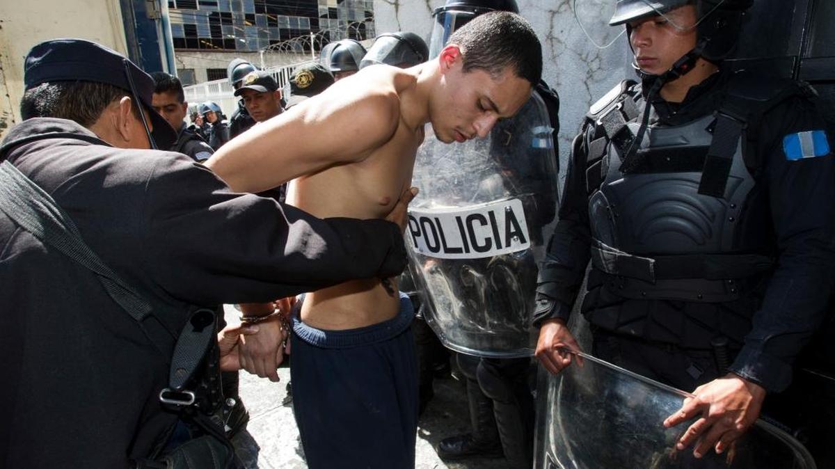 Un policía catea a un pandillero de Barrio 18 que participó en un motín reciente en una prisión, este martes en Guatemala.