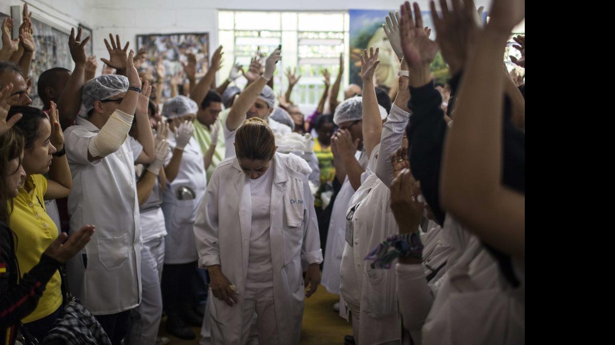 
La médium brasileña Eliane (cen.) reza con fieles y pacientes tras realizar cirugías y tratamiento el martes, en Sabará Brasil. 
