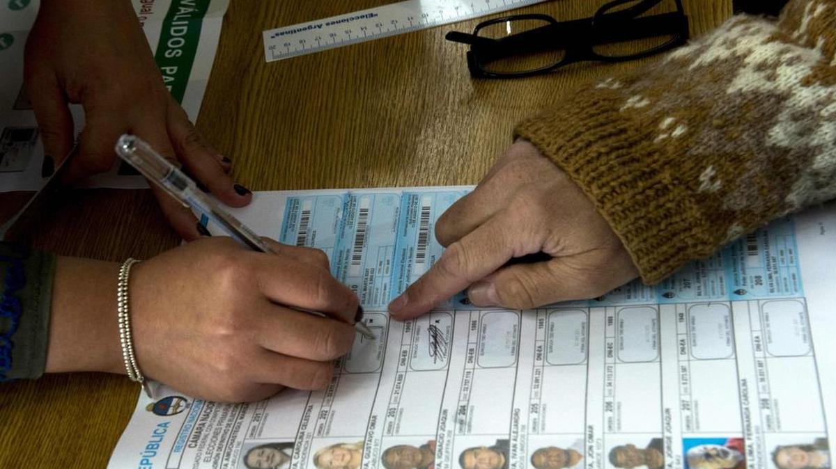Un funcionario de la mesa de votación comprueba la identificación de un votante durante las elecciones legislativas primarias en Buenos Aires el 13 de agosto de 2017.