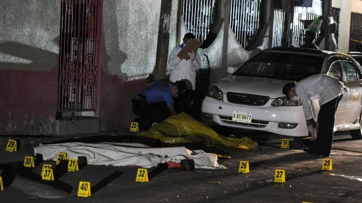 Miembros de la Oficina de Medicina Forense inspeccionan el cadáver de un hombre que se sospecha fue asesinado por pandilleros, el viernes en la noche, cuando varios desconocidos dispararon contra cuatro personas.