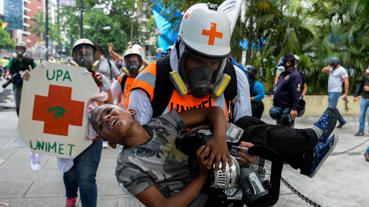 El personal médico lleva a un joven sufriendo los efectos del gas lacrimógeno durante los enfrentamientos entre los manifestantes de la oposición y la policía antidisturbios durante una protesta contra el gobierno del presidente Nicolás Maduro en Caracas, el 30 de mayo de 2017.