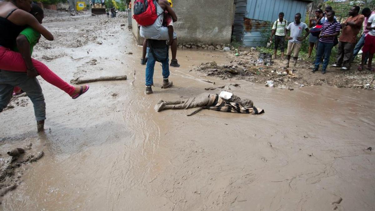
El cadáver de una persona es visto en una calle de Montrouis, Haití, luego de que residentes de la zona lo recuperaran del lodo el sábado, tras el paso de la tormenta tropical Erika.
