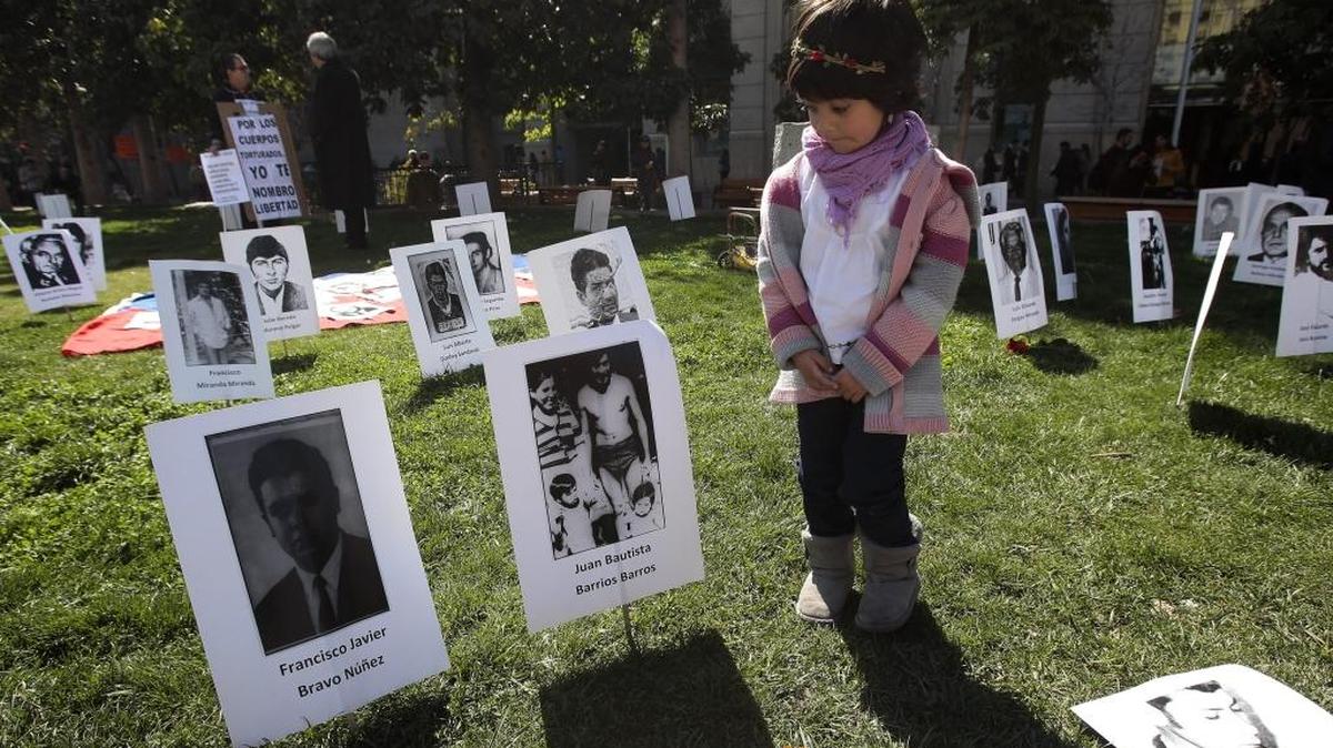 
Una niña observa el viernes, frente al Palacio de La Moneda, fotografías de detenidos desaparecidos en un acto homenaje a la víctimas del golpe de Estado militar de Augusto Pinochet, cuya dictadura dejó unas 3,200 víctimas.
