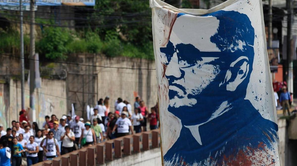 
Salvadoreños portan una pancarta con la imagen del arzobisto de San Salvador, Óscar Romero, durante la ceremonia de su beatificación en mayo. Romero fue asesinado en 1980 durante una misa.


