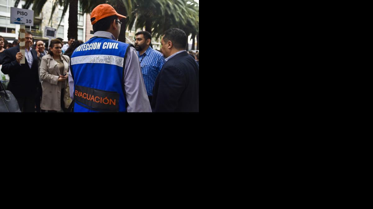 
Personal de Protección Civil da instrucciones a las personas evacuadas de los edificios por un temblor de tierra en Ciudad de México. 
