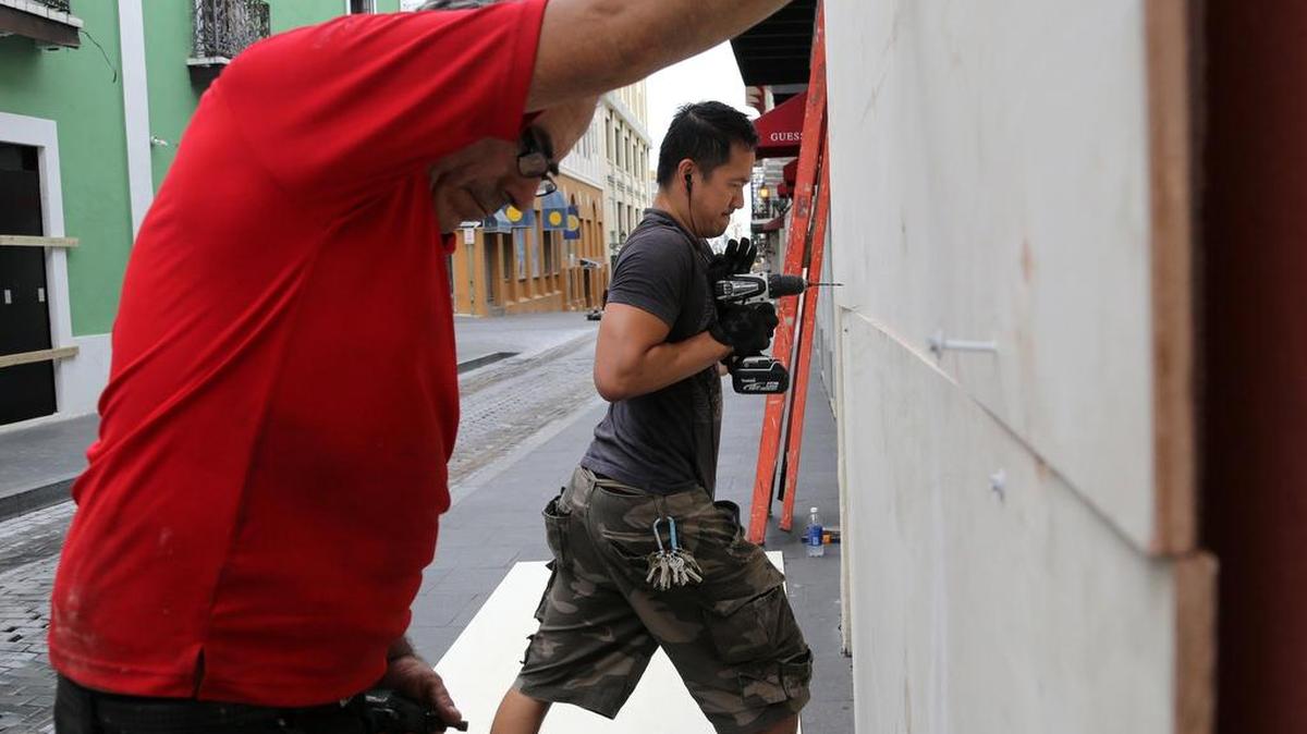 Daniel Hernández, izquierda, y Mario Baniaga trabajaban rápico elmartes para reforzar ventanas en el Viejo San Juan.