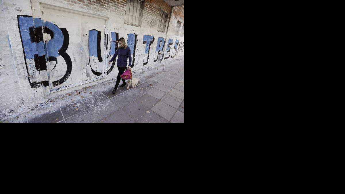 
Una mujer camina al lado de un mural relacionado con los llamados “Fondos buitres”, en Buenos Aires, en el 2014.
