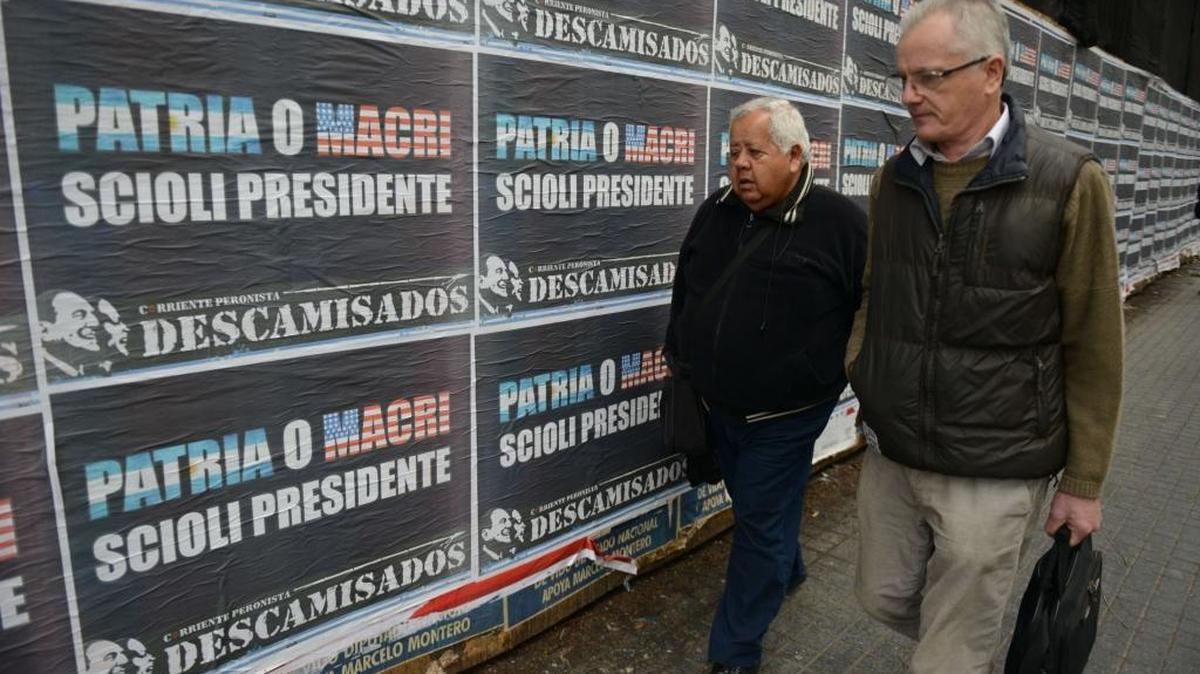 Dos hombres caminan frente a carteles de Daniel Scioli, en Buenos Aires. La segunda vuelta de las elecciones será el 22 de noviembre.
