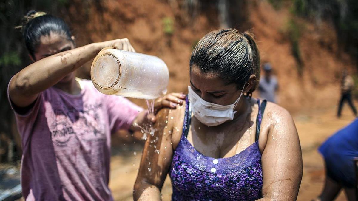 Una mujer se limpia este sábado tras intentar rescatar utensilios de su casa anegada por el lodo en Mariana, Brasil.