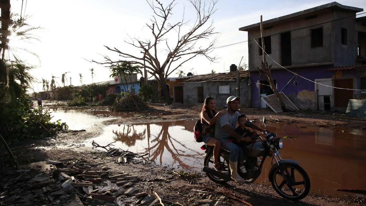Una familia transita en una motocicleta el sábado 24 de octubre de 2015, tras el paso del huracán Patricia en una calle de la comunidad de Emiliano Zapata (México).