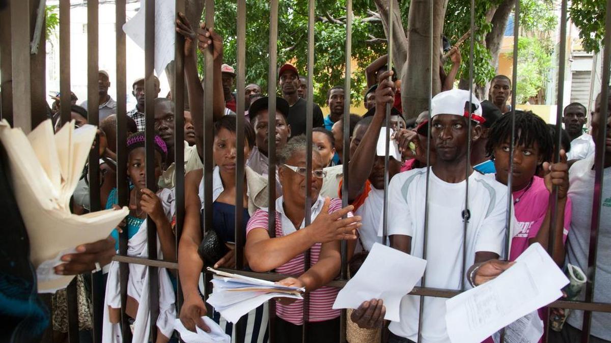 
Inmigrantes, principalmente haitianos, muestran su documentación mientras esperan para legalizar su residencia en República Dominicana, en junio.
