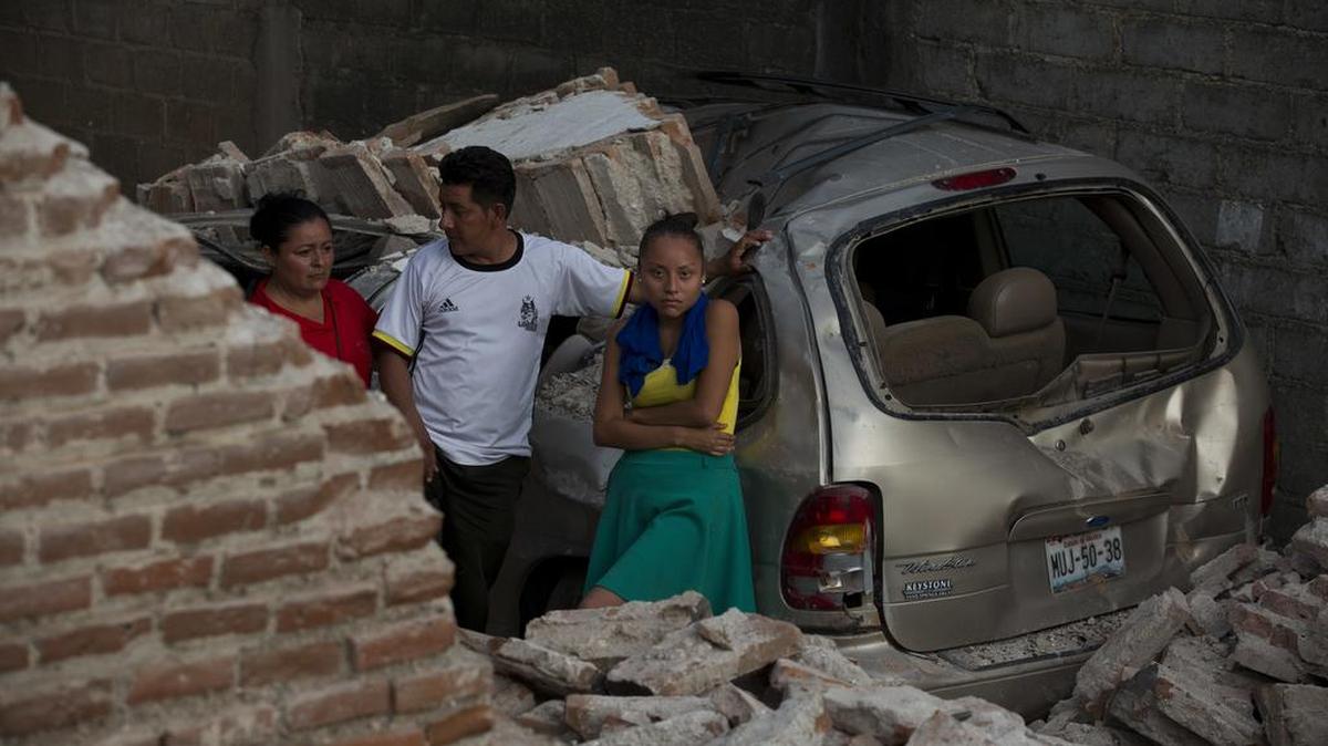 Una familia junto a su casa y auto destruido por el terremoto este sábado en la población de Juchitán, estado de Oaxaca, México.