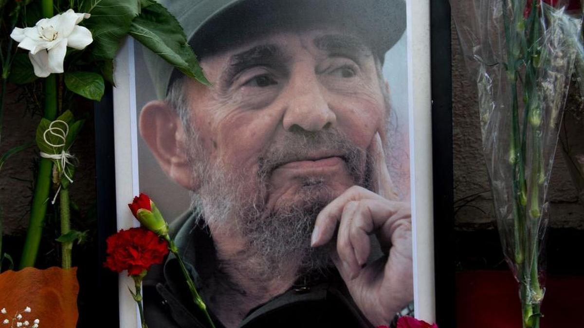 Un retrato del revolucionario líder cubano Fidel Castro está rodeado de flores mientras la gente se reúne fuera de la embajada cubana en Santiago el 26 de noviembre de 2016, al día siguiente de su muerte a los 90.