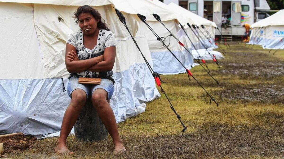 Una mujer espera afuera de una tienda en un centro de refugio para los damnificados del terremoto, el domingo 24 de abril de 2016, en Pedernales (Ecuador).