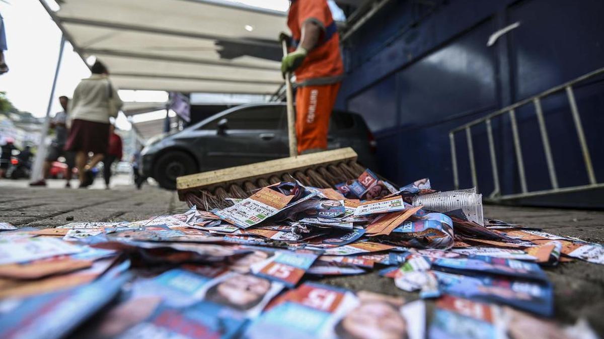 Un trabajador recoge papeles con propaganda política el domingo 2 de octubre de 2016, durante la jornada de elecciones municipales en un colegio electoral enfrente a la favela de Rocinha en Río de Janeiro (Brasil).