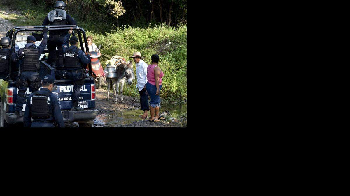 
Residentes de Iguala observan a policías y a soldados que conducen a expertos forenses a las fosas clandestinas donde se sospechan enterraron a varios de los 43 estudiantes desaparecidos en Iguala, México.
