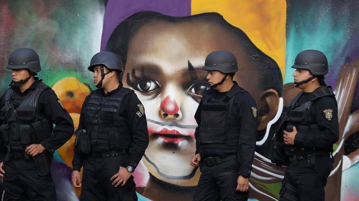Fuerzas policiales desplegadas frente a un mural de arte callejero mientras miles de personas marchan para protestar contra el gobierno mexicano tras un alza de 20 por ciento en el combustible, en la Ciudad de México el 9 de enero del 2017.