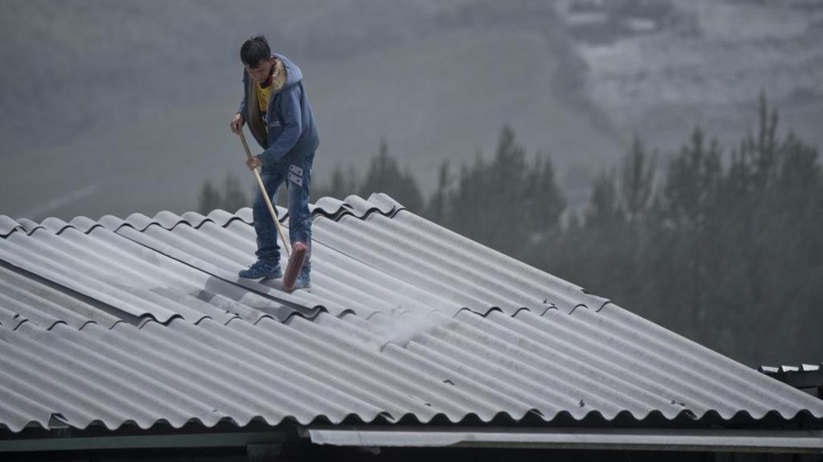 
Un hombre limpia el sábado el techo de su casa cubierto de cenizas del volcán Cotopaxi, en Machachi, Ecuador.
