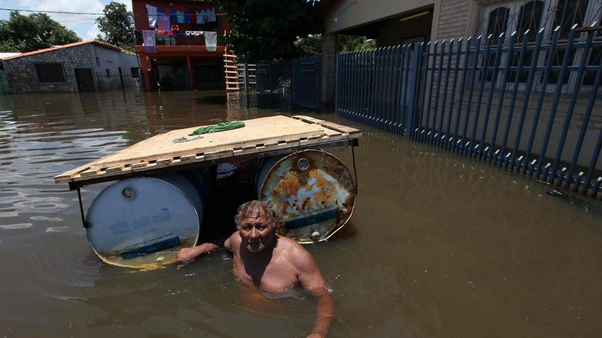 Un hombre lleva una balsa el jueves, en un barrio inundado de Asunción, Paraguay.