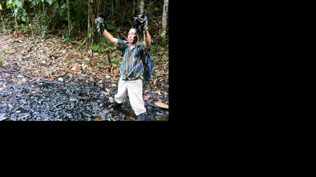 
Un lider indigena de la organización conservacionista PUINAMUDT muestra la contaminación de petroleo en el río Corrientes de la selva peruana.
