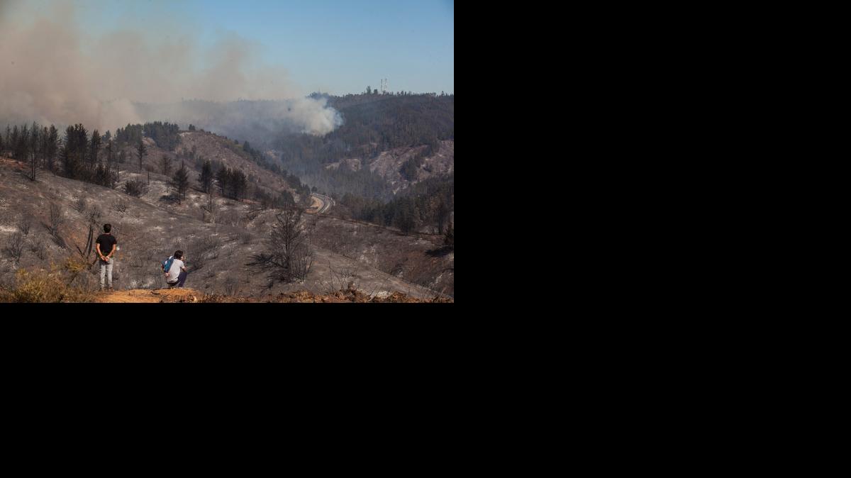 
Vecinos del sector observan el sábado el área devastada en el sector de Rodelillos, donde se propagó un incendio de grandes dimensiones que afectó a la perifería de la ciudad de Valparaiso, Chile. 
