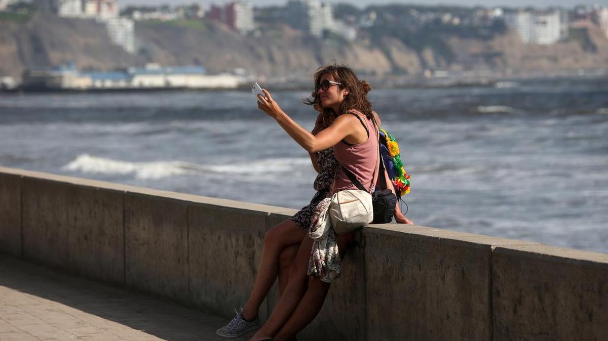 Turistas se toman fotografías este miércoles, 6 de enero de 2016, en las playas de la Costa Verde de Lima (Perú).