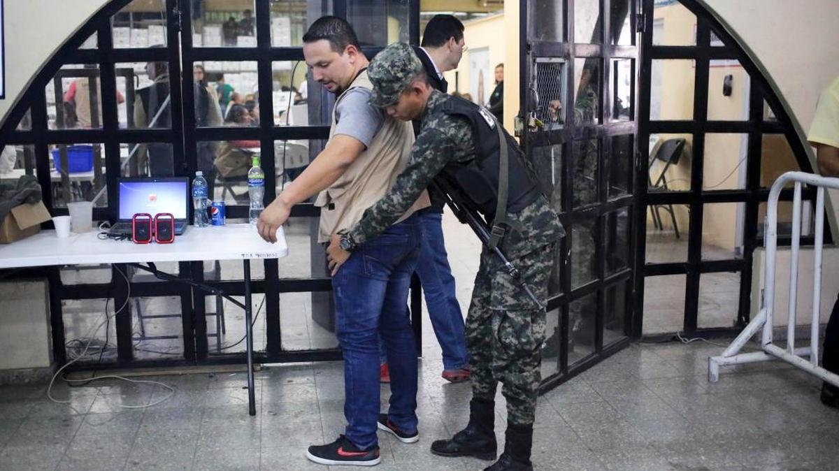 Un militar cachea a un empleado del Tribunal Supremo Electoral (TSE) de Honduras el martes antes de entrar a la sala donde se realiza el escrutinio especial de las elecciones generales.