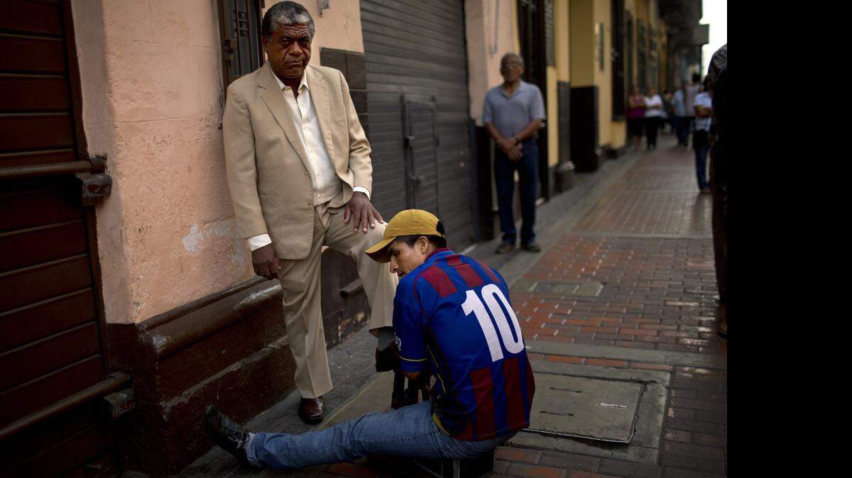 
Un lustrabotas ejerce su oficio en una calle de Lima, Perú, donde la pobraza sigue reduciéndose.
