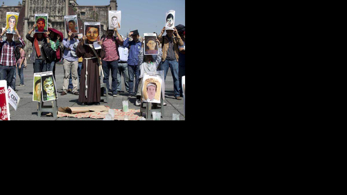 
Los manifestantes sostienen carteles que muestran retratos de algunos de los 43 estudiantes desaparecidos, durante una oración y protesta en el Zócalo, la plaza principal de la Ciudad de México, el jueves, 6 de noviembre de 2014. 

