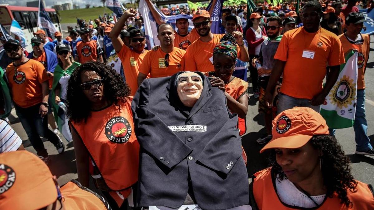 Manifestantes participan en una protesta el miércoles 24 de mayo de 2017, en la Explanada de los Ministerios en Brasilia (Brasil). La capital brasileña amaneció con un fuerte refuerzo policial, todas sus principales avenidas cerradas y un monumental caos de tránsito, frente a una protesta de sindicatos que exige la "renuncia inmediata" del presidente Michel Temer. El mandatario está bajo fuego cruzado desde la semana pasada por unas confesiones de directivos del grupo JBS que lo implican directamente en hechos de presunta corrupción, por los que la Corte Suprema ha decidido iniciar una investigación.