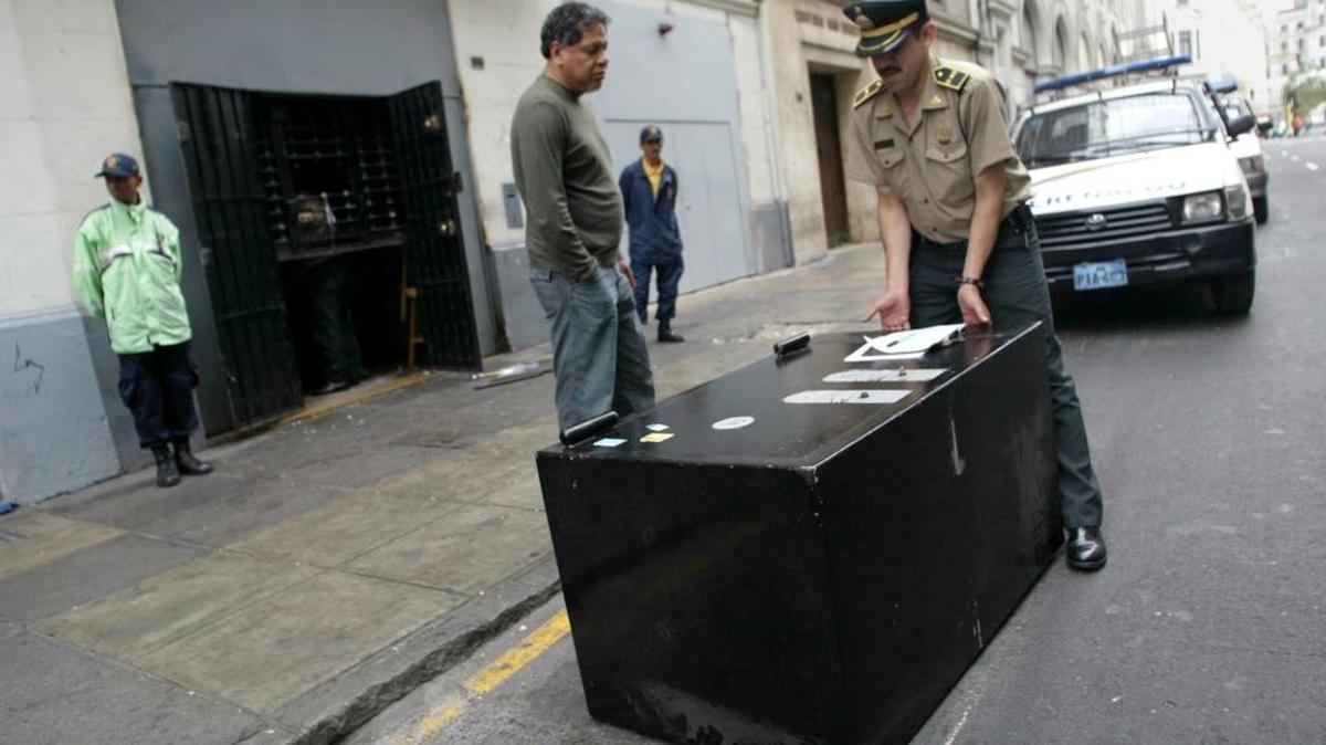 
Un policía intenta empujar una caja fuerte despúes de que cuatro ladrones peruanos se vieran forzados a abandonarla al no poder con su peso, en el centro de Lima. Foto Archivo.
