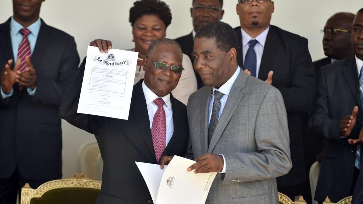 El presidente provisional de Haití, Jocelerme Privert (izq.), muestra el lunes el documento oficial que designa a Enex Jean-Charles(der.), como primer ministro de ese país, en una ceremonia en la que anunció que, en las próximas 24 horas, se conformará un nuevo Consejo Electoral Provisional.
