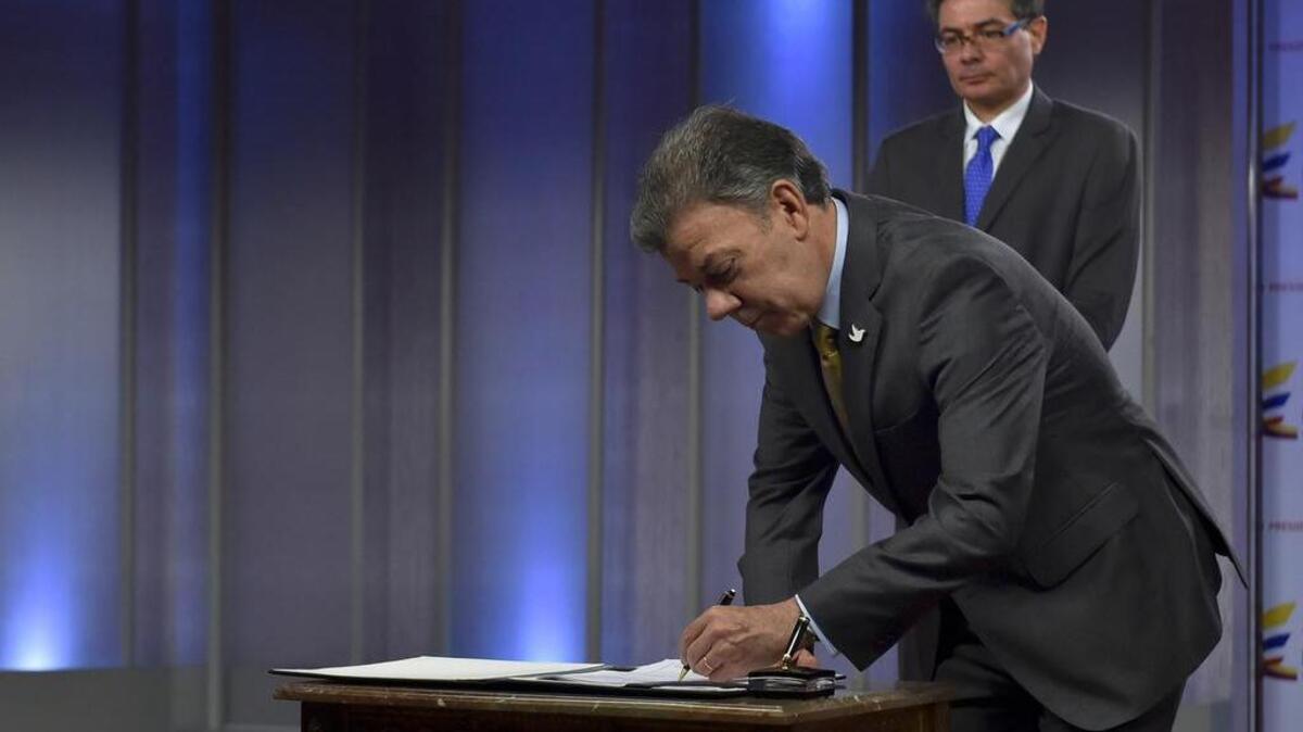 El momento en que el presidente de Colombia, Juan Mannuel Santos (izq.) firma el decreto de legalización de la marihuana para uso médico en Bogotá, el 22 de diciembre 2015. Está junto al ministro de Salud, Alejandro Gaviria.