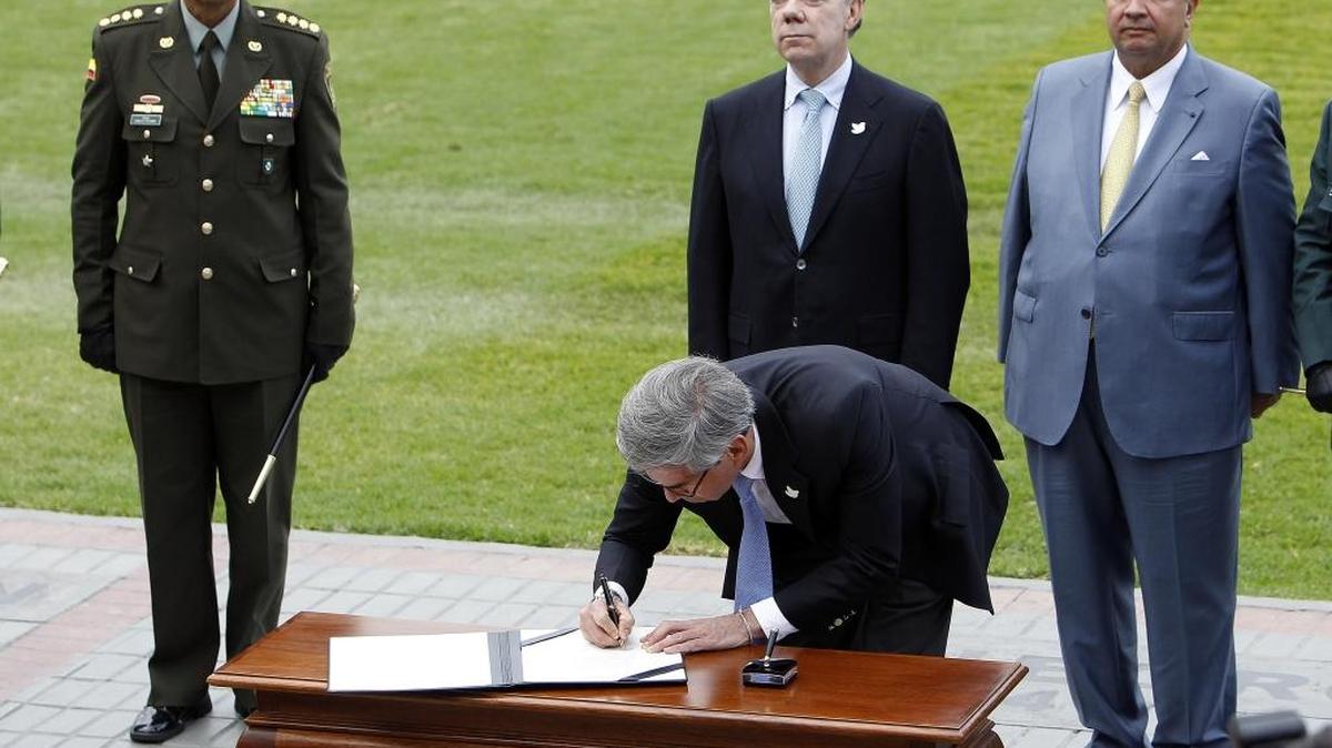 El presidente de Colombia, Juan Manuel Santos (2 izq.), observa al ministro de Justicia, Yesid Reyes, durante la firma de un compromiso del gobierno “con la resolución definitiva de la situación jurídica de los agentes del Estado”.