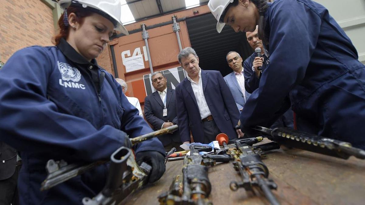 El presidente colombiano Juan Manuel Santos ve como observadores de la ONU inutilizan armas entregadas por las FARC, el viernes en el poblado de Funza, en las afueras de Bogotá.