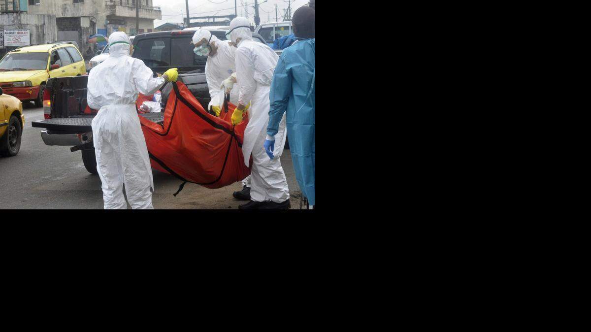 
Trabajadores del sector de la salud trasladan a una persona que se sospecha murió de ébola en las calles de Monrovia, Liberia, el lunes. 
