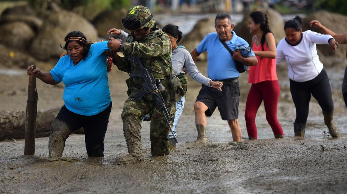 Un soldado ayuda a una mujer después de una avalancha del río La Paila el miércoles 08 de noviembre de 2017, en el municipio de Corinto, departamento del Cauca (Colombia).