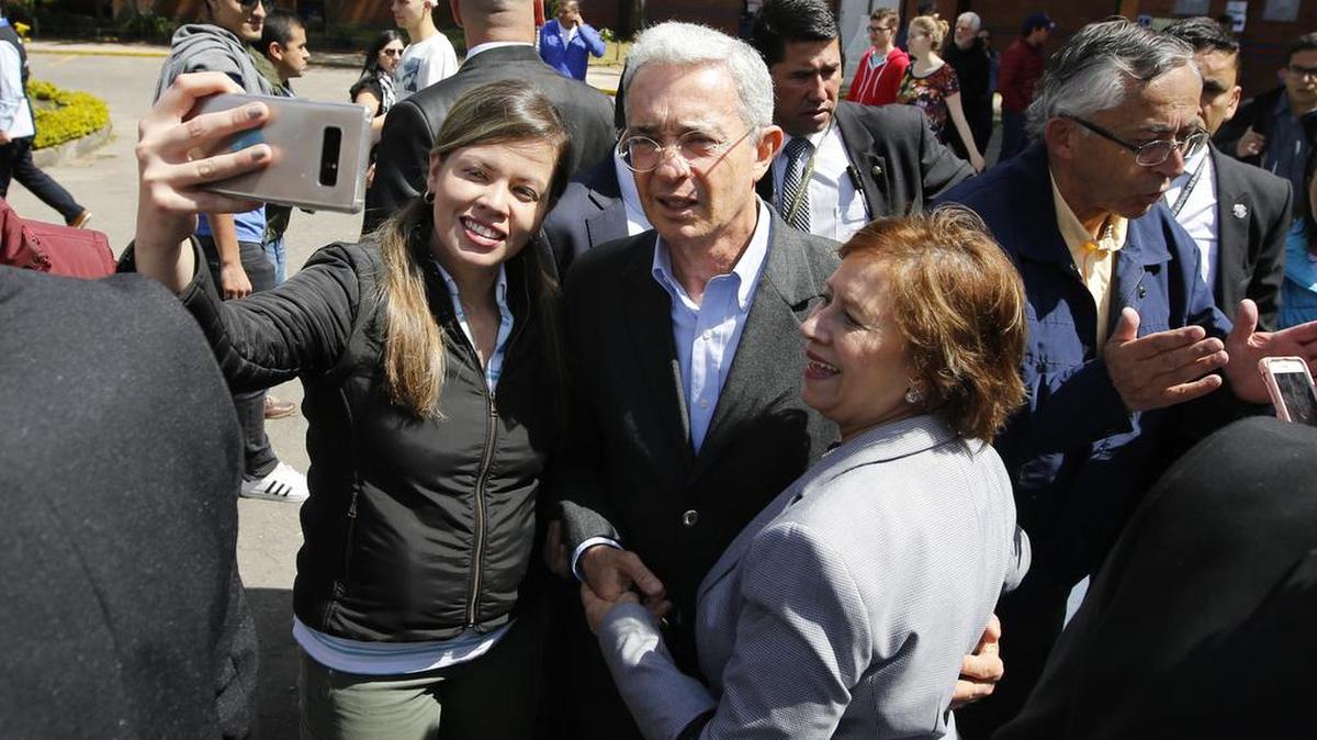 El ex presidente colombiano Álvaro Uribe posa junto a simpatizantes el domingo 11 de marzo en un centro de votación en Bogotá.