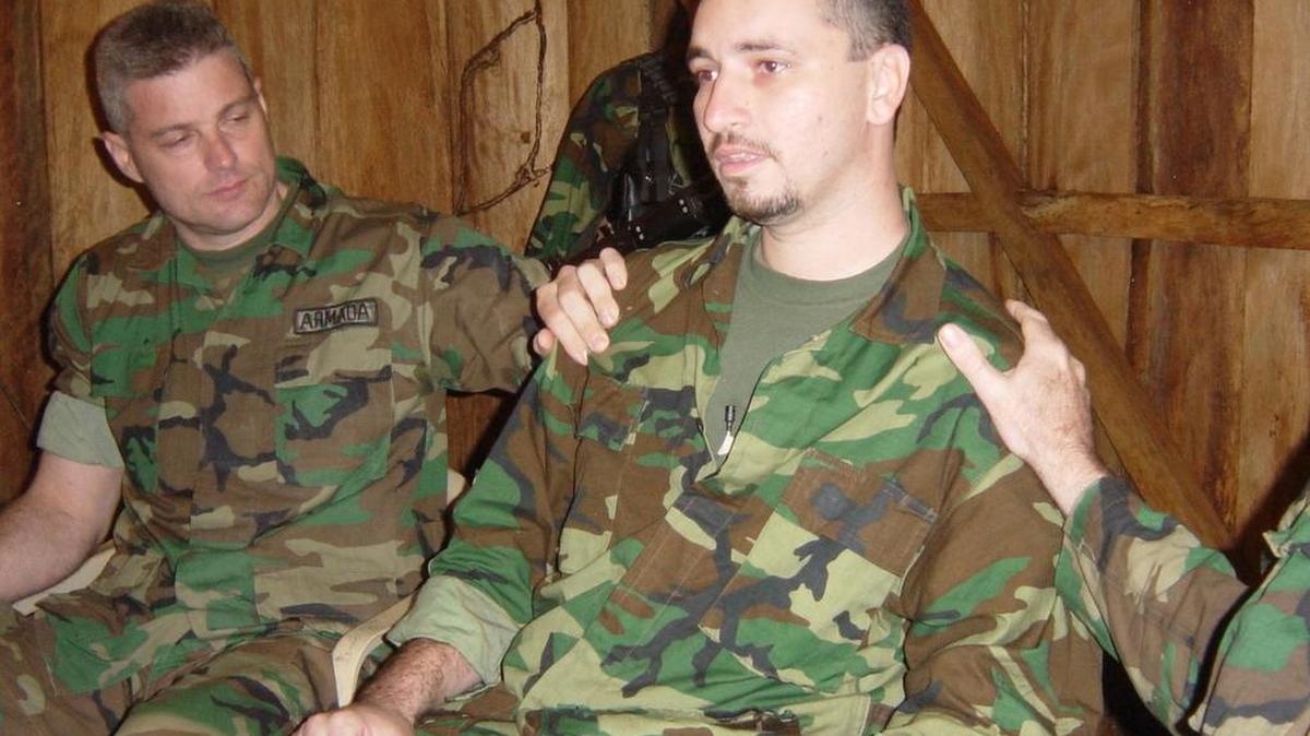 Marc Gonsalves (centro) es consolado por Keith Stansell (izq.) y Tom Howes (imagen parcial a la der.), cuando miraba un mensaje de video grabado por su madre, Jo Rosano, el 25 de julio de 2003. Los tres ciudadanos estadounidenses estaban secuestrados en un lugar no identificado en el sur de Colombia.