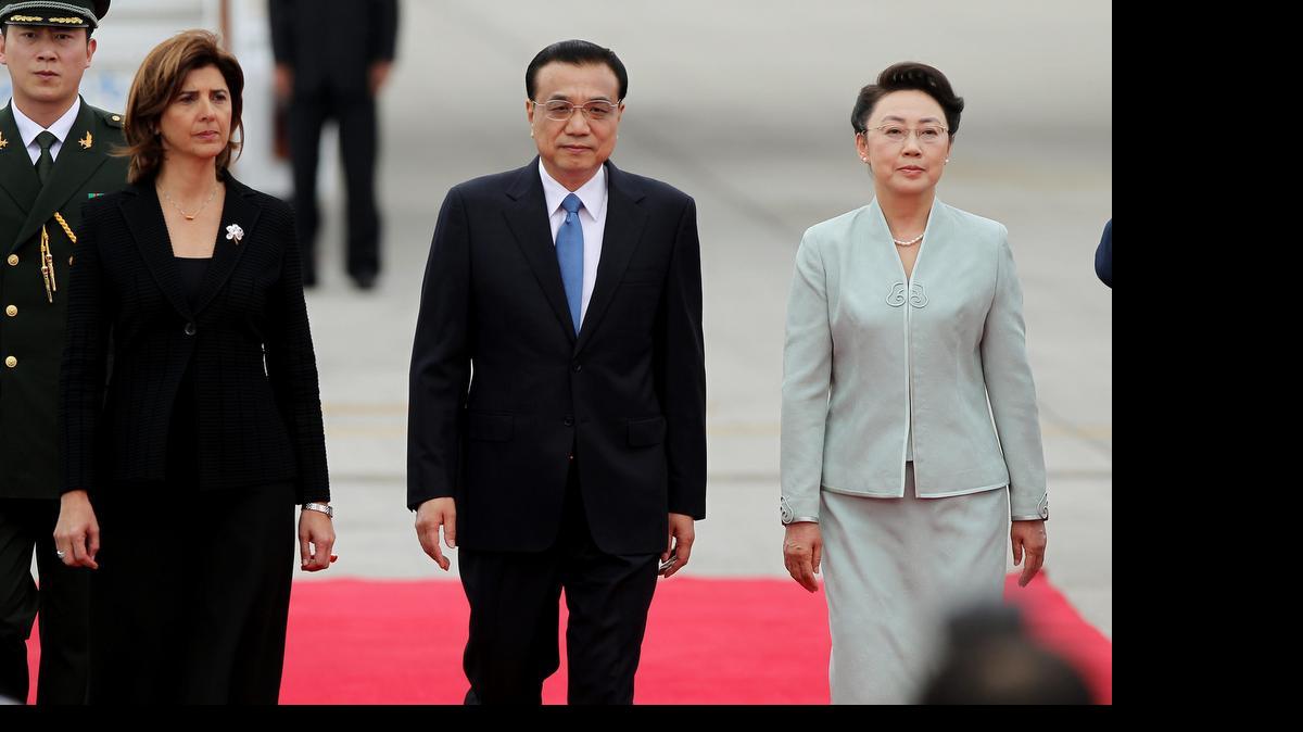 
El primer ministro de China, Li Keqiang (cent.), camina acompañado de su esposa, Cheng Hong (der.), y la ministra de Relaciones Exteriores de Colombia, María Ángela Holguín (izq.), a su llegada el jueves a Bogotá, Colombia. 
