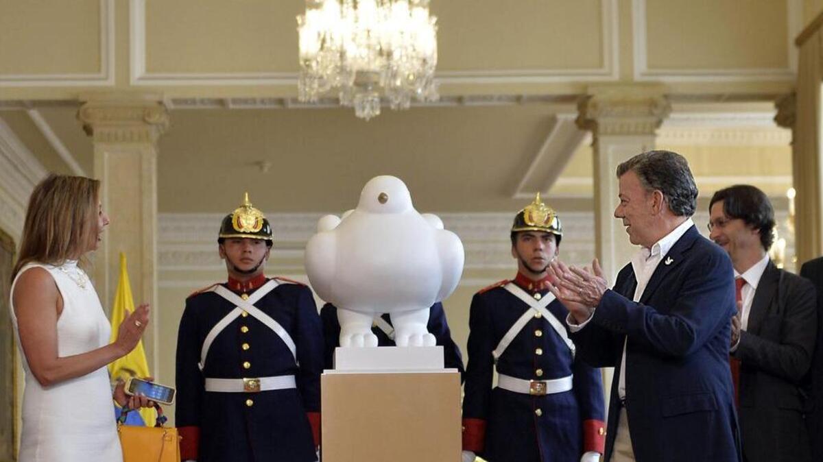 El presidente de Colombia, Juan Manuel Santos (der.) recibe la escultura 'La paloma de la paz', un regalo del artista colombiano Fernando Botero, en el palacio presidencial de Nariño en Bogotá, el 24 de septiembre de 2016.