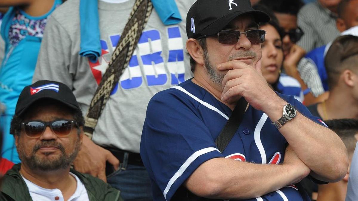 El jefe de las FARC, Timoleón Jiménez, alias “Timochenko” (der.) y el comandante Iván Márquez (izq.) asisten al partido de béisbol entre los Tampa Bay Rays y la selección de Cuba, el martes en La Habana.