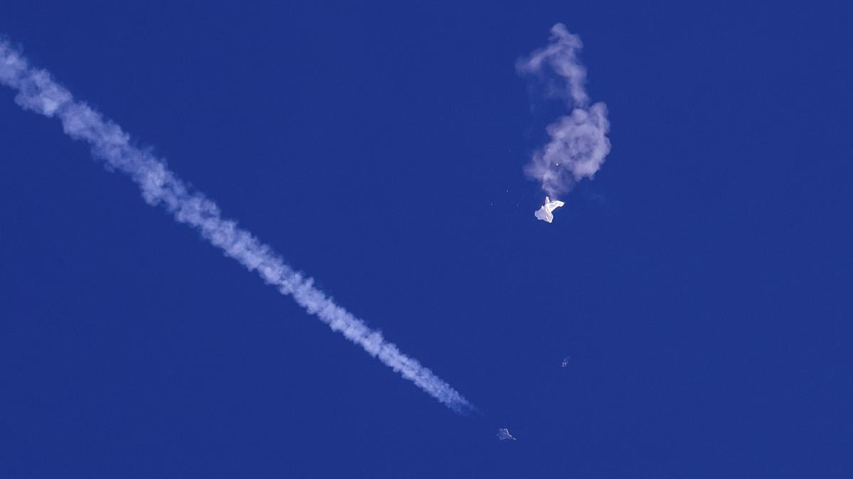 Fotografía proporcionada por Chad Fish de los restos de un globo sobre el océano Atlántico en la costa de Carolina del Sur con un avión de combate y su estela debajo, el sábado 4 de febrero de 2023. (Chad Fish vía AP)